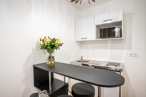une cuisine avec une table noire et un vase de fleurs dans l'établissement 147 - Urban Cosy Flat in Paris, à Paris