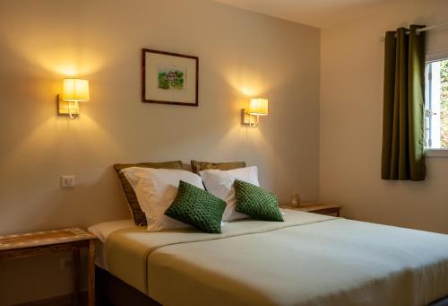 una camera da letto con un letto con cuscini verdi e bianchi di Avalon a Grospierres