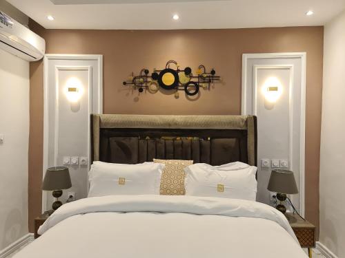una camera da letto con un grande letto bianco con due luci di Suna' a Home Bonapriso a Douala