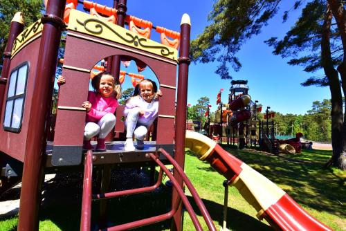 two little girls sitting on a slide at a playground at Aquapark Health Resort & Medical SPA Panorama Morska All Inclusive in Jarosławiec