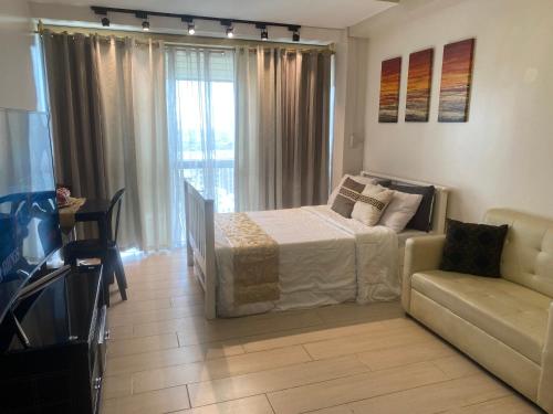 ein Schlafzimmer mit einem Bett, einem Sofa und einem TV in der Unterkunft The Haven 2 at One Eastwood Ave Tower 1 with Amazing View in Manila