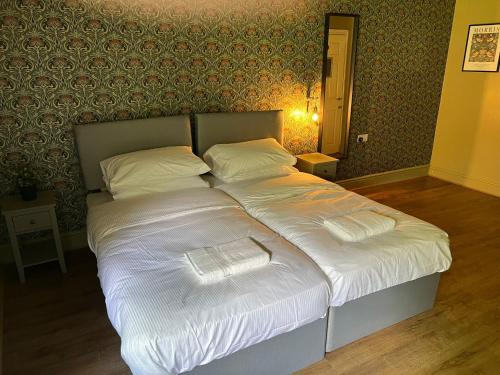 a bed with white sheets and pillows in a bedroom at The Ring O'Bells in Halifax