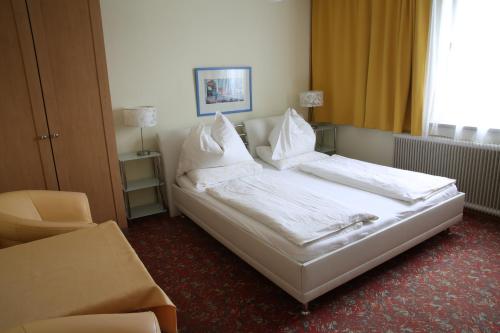 Schlafzimmer mit einem Bett mit weißer Bettwäsche und Kissen in der Unterkunft Hotel Reinisch in Köflach