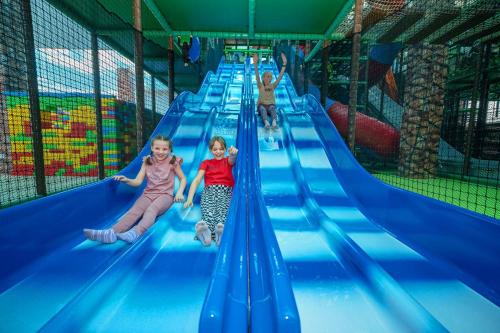 three children are riding down an inflatable slide at an indoor playground at Aquapark Health Resort & Medical SPA Panorama Morska All Inclusive in Jarosławiec