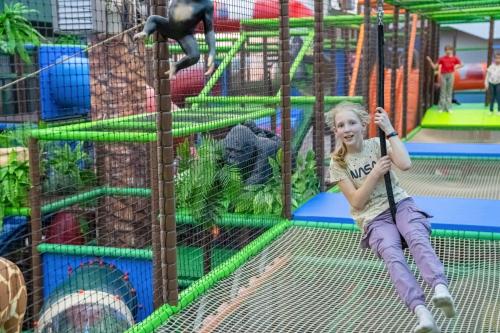 a little girl sitting on a swing at a playground at Aquapark Health Resort & Medical SPA Panorama Morska All Inclusive in Jarosławiec