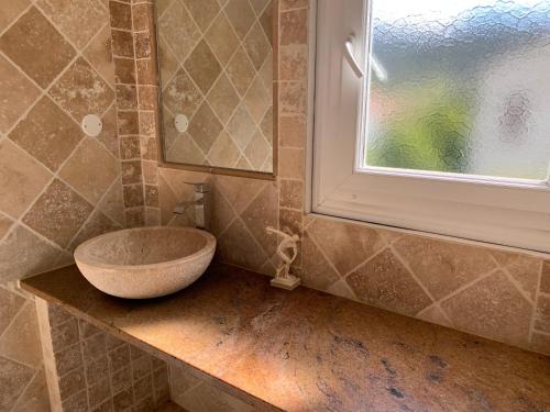 a bathroom with a sink on a counter with a window at Maison de village tout confort in Eccica-Suarella