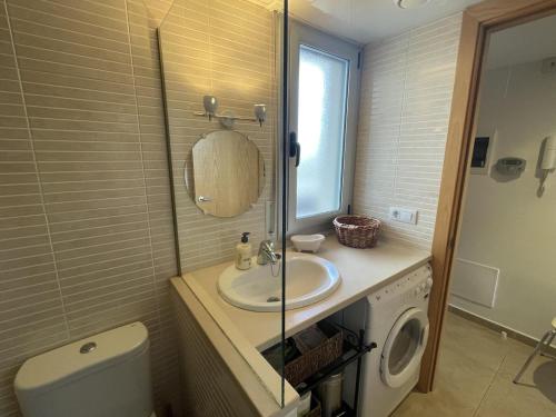 uma casa de banho com um lavatório e uma máquina de lavar roupa em Les Marines em Roses