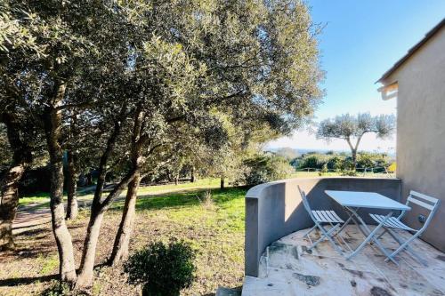 une table et deux chaises assises à côté d'un arbre dans l'établissement Charmant studio maquis vue citadelle de Bonifacio, à Bonifacio