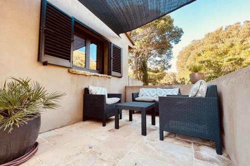 un patio avec des chaises, une table et une fenêtre dans l'établissement Charmant studio maquis vue citadelle de Bonifacio, à Bonifacio