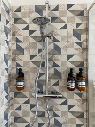 a shower with three bottles on a tiled wall at Valtellina Vacanze in Sondrio
