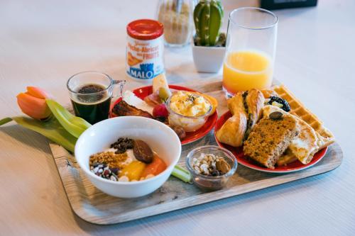 a tray of breakfast foods and a glass of orange juice at ibis Saint Malo Plage in Saint Malo