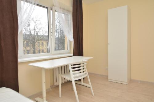 een witte tafel en een stoel in een kamer met een raam bij Vytauto av 9 - Kaunas Students Home LT in Kaunas