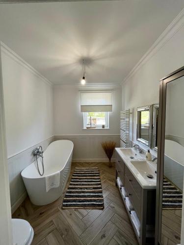 a white bathroom with a tub and a sink at Lake House Family in Wiewiecko