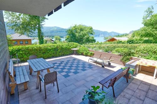 eine Terrasse mit einem Tisch, Stühlen und einer Bank in der Unterkunft Ferienwohnungen Landhaus Gerum in St. Wolfgang