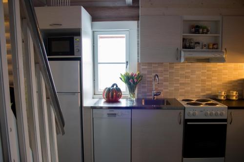 a kitchen with white appliances and a sink and a window at Villa Kurpitsa at MESSILA ski & camping in Hollola