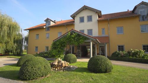a large yellow building with bushes in front of it at Landhotel Larenzen in Kirchham