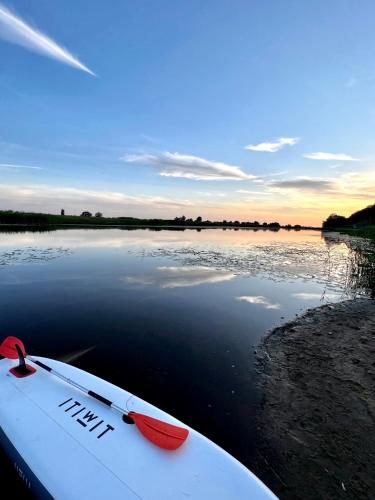 a surfboard sitting on the shore of a body of water at Houses with a View#Sauna#Jaccuzi in Gozdowice