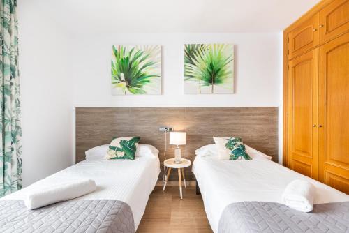 ein Schlafzimmer mit zwei Betten und einem Tisch mit Lampe in der Unterkunft Apartamento Moderno Calle Larios in Málaga