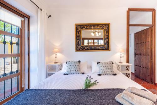 ein Schlafzimmer mit einem weißen Bett und einem Spiegel in der Unterkunft Casa de los Sueños in Villanueva del Rosario