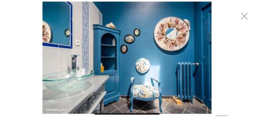 baño con paredes azules, lavamanos y silla en La Maison Blanche à Saint-Yzans-de-Médoc en Saint-Yzans-de-Médoc