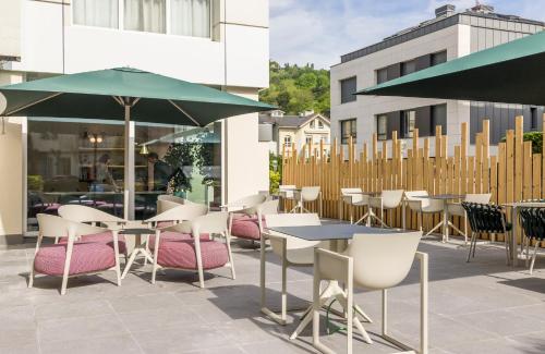a group of tables and chairs with umbrellas on a patio at Hotel Ilunion San Sebastián in Donostia-San Sebastián