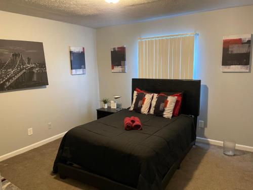 a bedroom with a black bed with a pair of red shoes on it at 2Bdrm Comfortable Townhome 5 Mins from Airport in Atlanta