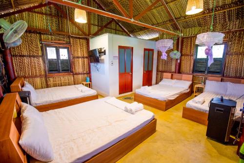 una camera con quattro letti in una capanna di paglia di The River Home a Nhơn Trạch