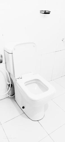 a white toilet in a bathroom with a white floor at SURF & SAND Hotel Arugambay in Arugam Bay