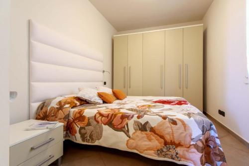 a bedroom with a bed with a floral comforter at Appartamento Verdemare in Diano Marina