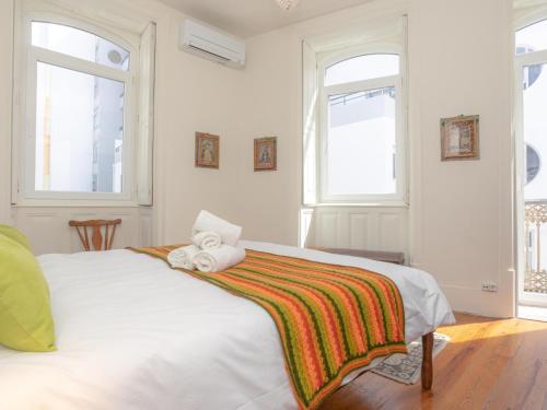 ein weißes Schlafzimmer mit einem Bett und einem Handtuch darauf in der Unterkunft Casa do Poeta in Figueira da Foz