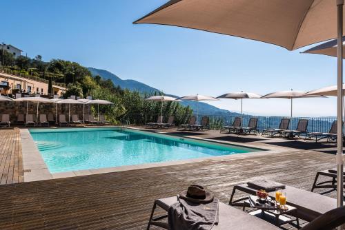 a swimming pool with chairs and umbrellas and the ocean at Villa Guinigi Dimora di Epoca Exclusive Residence & Pool in Lucca