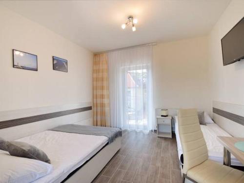 a bedroom with two beds and a desk and a television at Dorato24 in Mrzeżyno