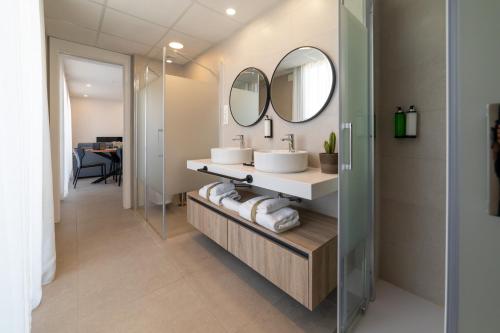 a bathroom with two sinks and two mirrors at Alidreams Lola Center Apartamentos in Alicante