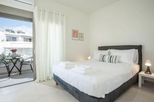 Habitación blanca con cama y balcón. en Cozy Apartment in the heart of Rhodes City Center en Rodas