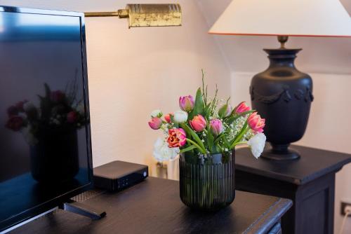 a vase of flowers on a table next to a lamp at Hotel Stadt Gütersloh in Gütersloh