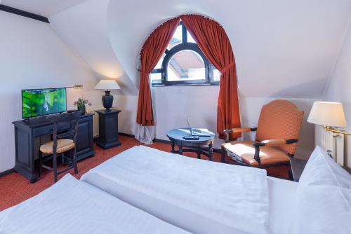 um quarto com uma cama, uma televisão e uma janela em Hotel Stadt Gütersloh em Gütersloh