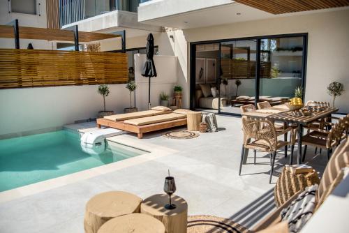 um pátio exterior com uma piscina, mesas e cadeiras em Ambient Living em Preveza