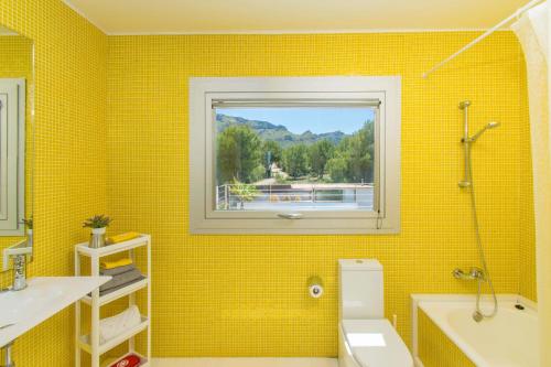une salle de bains jaune avec lavabo et fenêtre. dans l'établissement Casa Mut, à Artà