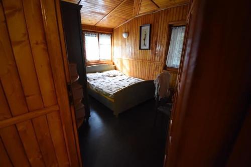 a small bedroom with a bed in a wooden room at Domek u Justy. in Pojezierze