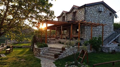 a stone house with the sun setting behind it at Village house - Novak Rijecani in Rijeka Crnojevića