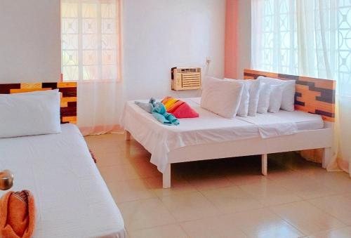 a bedroom with a bed with white sheets and colorful pillows at RedDoorz @ Jmalls Island Tourist Inn Dinagat Island in Odok