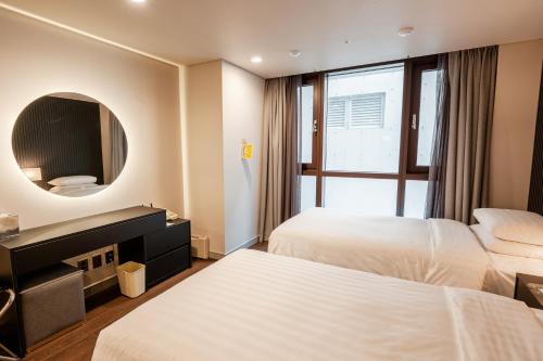 a hotel room with two beds and a mirror at Haeundae Centum Hotel in Busan