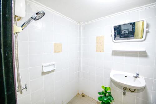 a white bathroom with a sink and a shower at Hotel Denmark - Beachfront in Jomtien Beach