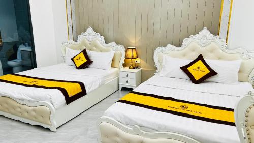 two beds in a bedroom with white and yellow sheets at Khach sạn Starfish Tuy Hoà in Tuy Hoa