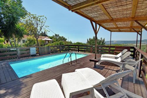 una terraza con piscina y sillas y una piscina en Biktot Nofim, en Manot
