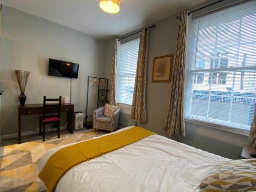 a bedroom with a bed and a desk and windows at Bristol Old City Studio in Bristol