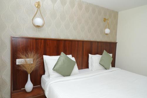 a bedroom with a bed with white and green pillows at Earth Hotels in Bengaluru