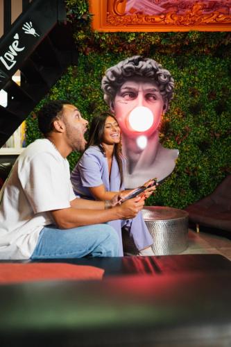 a man and a woman sitting in front of a statue at Capsule Art Déco - Jacuzzi - Netflix - Home Cinéma - Arcade de jeux & Nintendo switch - 2 chambres - Filet suspendu in Valenciennes