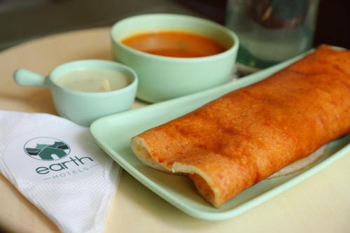 a plate of food with a sandwich and a cup of soup at Earth Hotels in Bengaluru