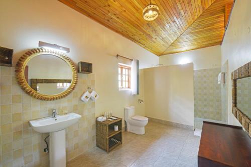 a bathroom with a sink and a mirror and a toilet at Parkview Safari Lodge-Kyambura in Busonga